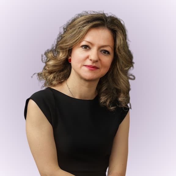 Maja Kovacevic Coupé, a smiling woman with glasses with blonde hair, wearing a black coat