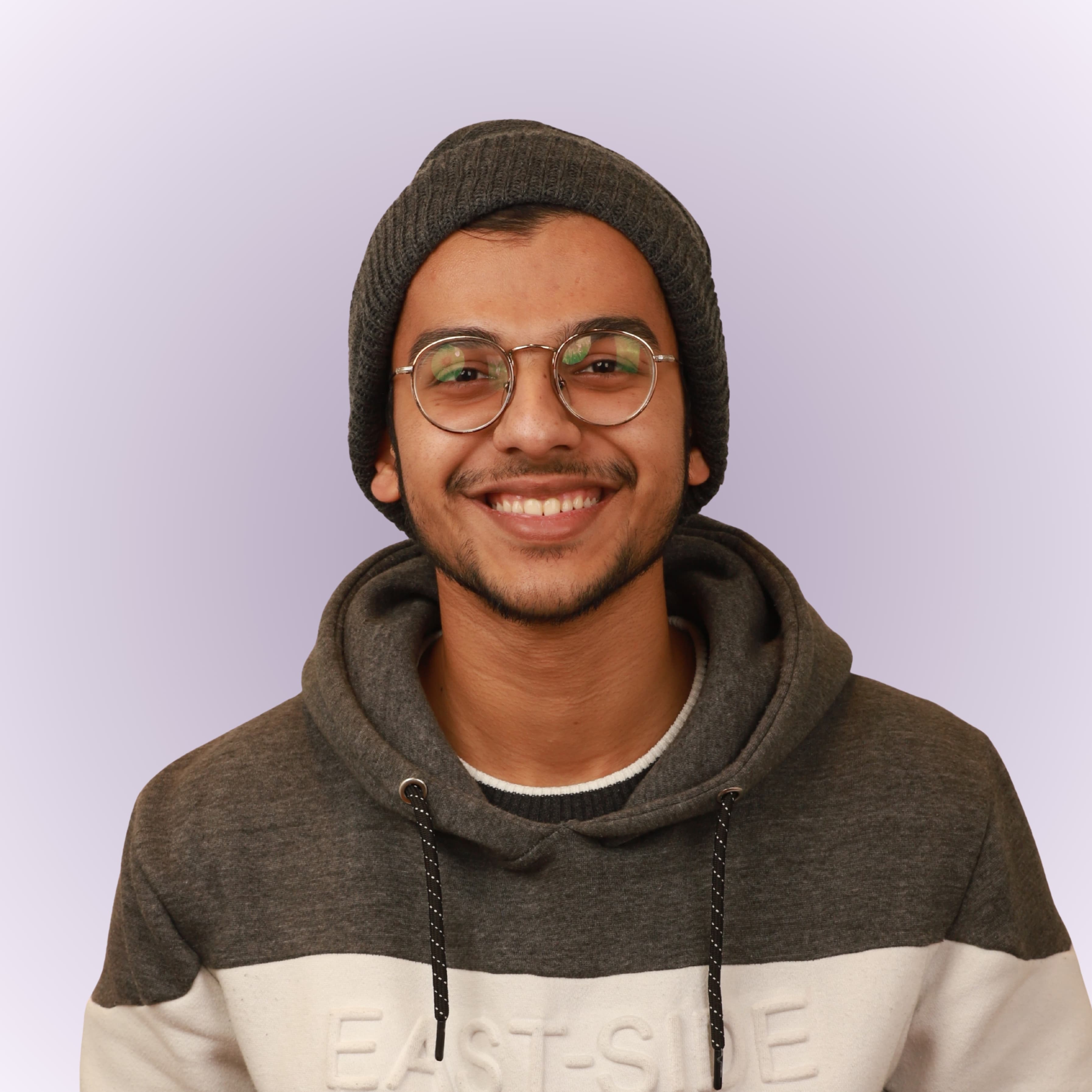 Syed Ali Mansoor, a smiling man with glasses, wearing a beanie and a gray hoodie
